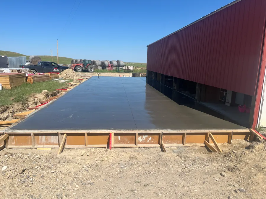 Freshly finished concrete slab beside a red steel building