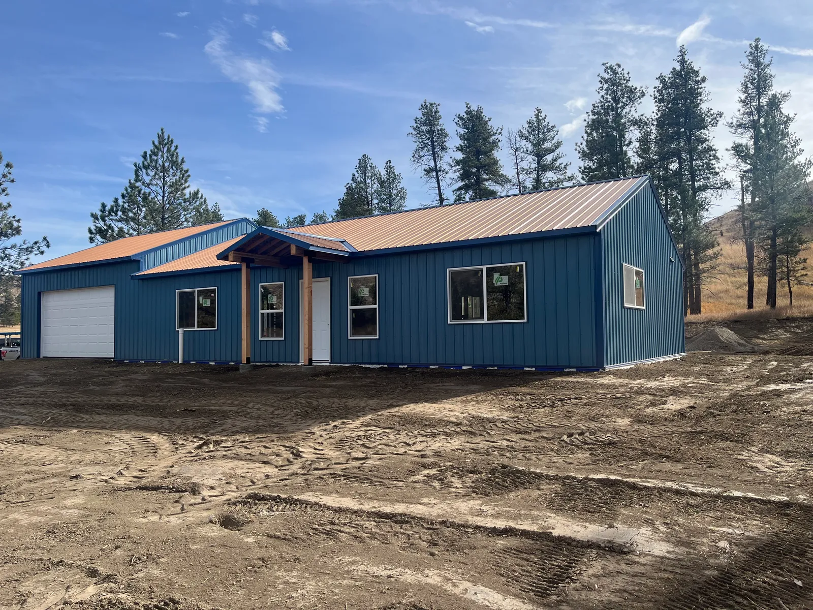 Completed custom home with blue siding and a red metal roof near Billings, Montana